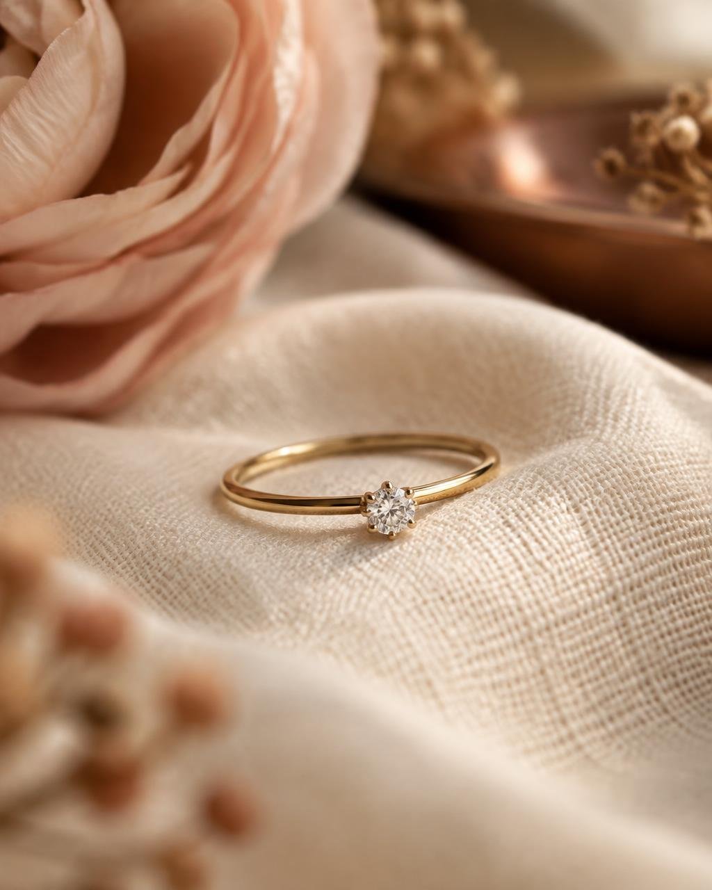 Slim gold ring with a small round diamond on linen