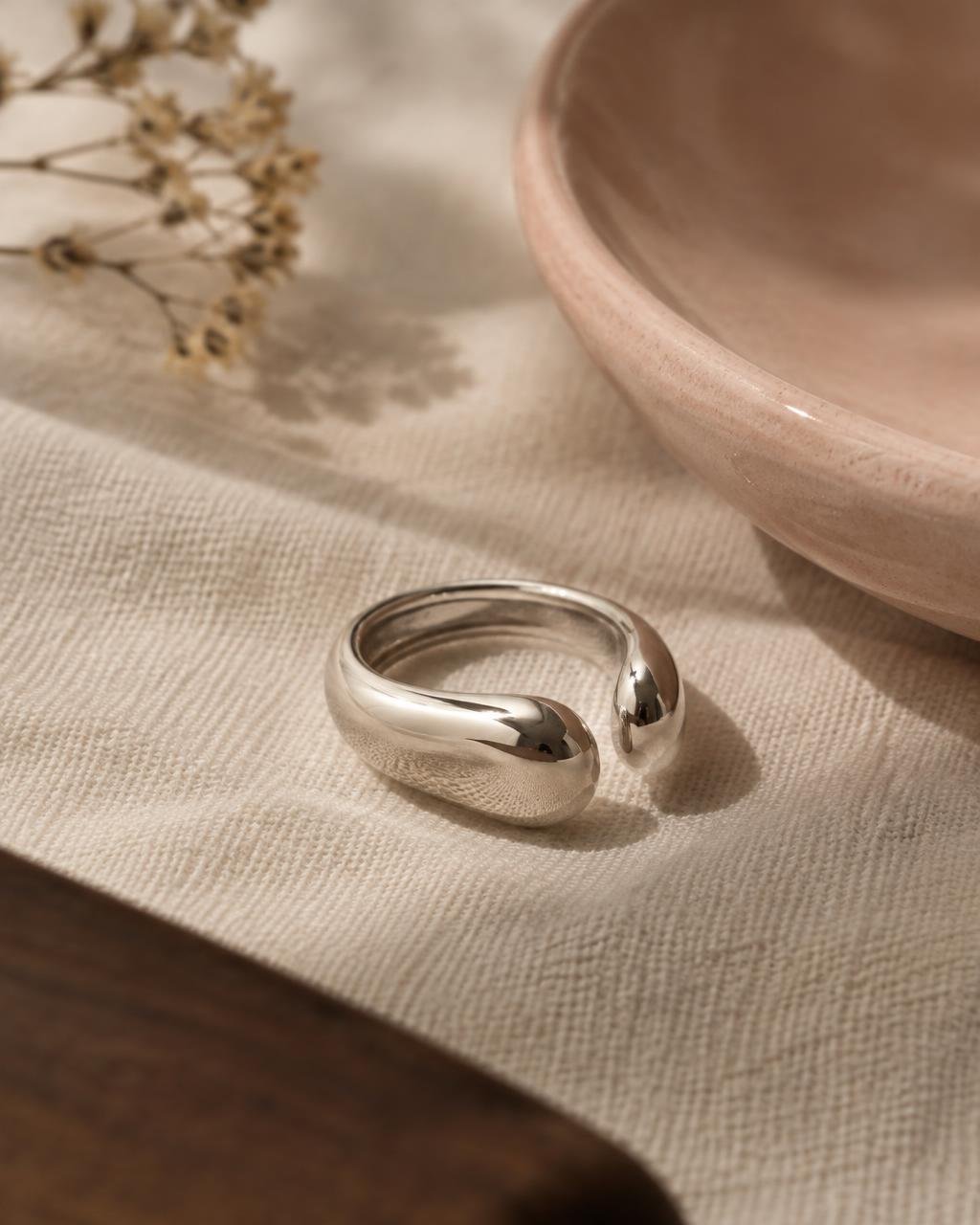 Polished sterling silver open ring on off-white linen